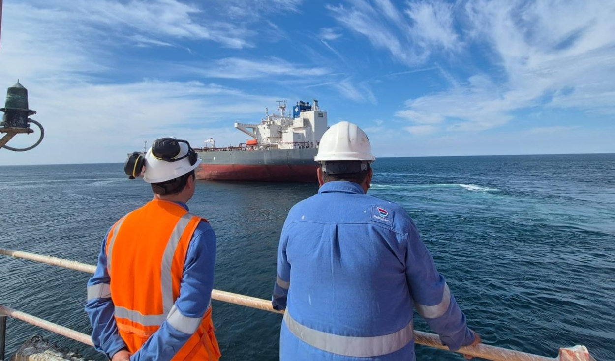Trabajadores de Petroperú observan un buque petrolero durante una operación marítima en la costa peruana.